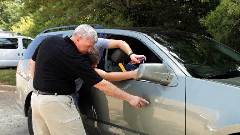 A trainer demonstrates vehicle exit techniques to a student, focusing on safety protocols during a practice scenario.
